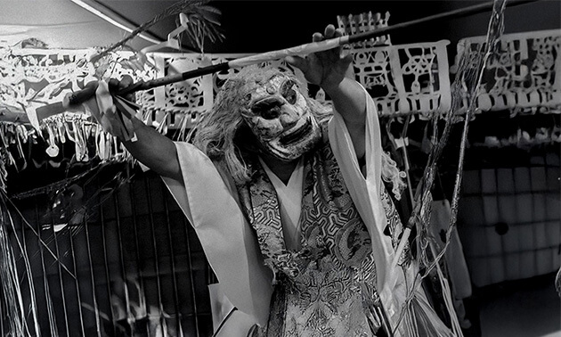 両手で杖をもつ神楽面