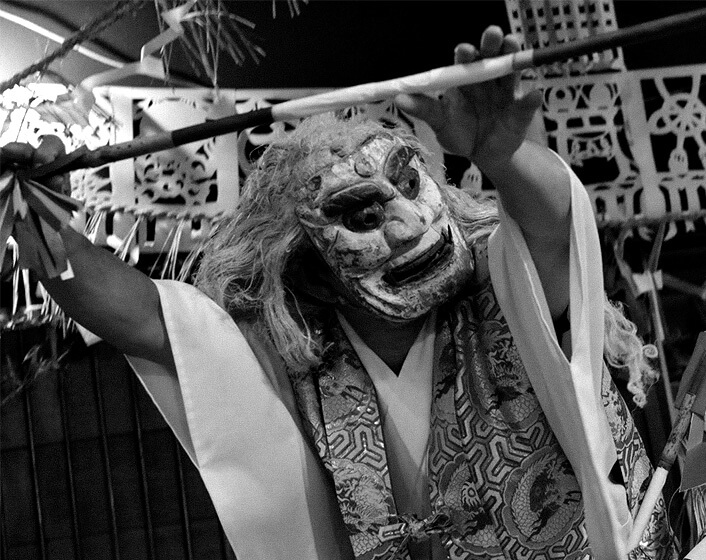 両手で杖をもつ神楽面
